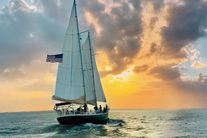 Sailboat on ocean at sunset with American flag.